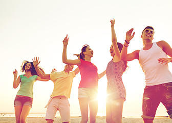 Image showing smiling friends dancing on summer beach