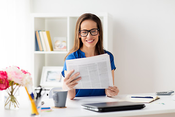 Image showing happy woman in glasses reading newspaper at office