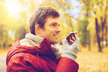 Image showing man recording voice on smartphone at autumn park