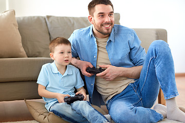 Image showing father and son playing video game at home