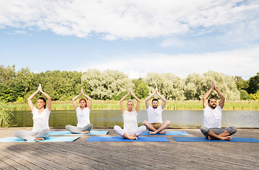Image showing people meditating in yoga lotus pose outdoors