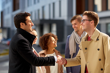 Image showing happy people shaking hands on city street