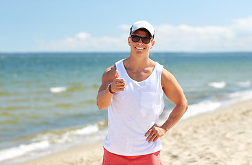 Image showing smiling man on summer beach showing thumbs up
