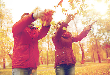 Image showing happy young couple throwing autumn leaves in park