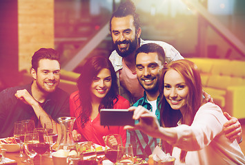 Image showing friends taking selfie by smartphone at restaurant