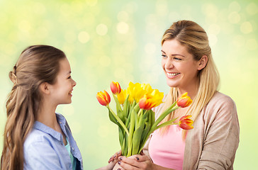 Image showing happy girl giving flowers to mother over lights