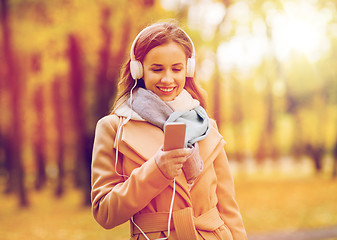 Image showing woman with smartphone and earphones in autumn park