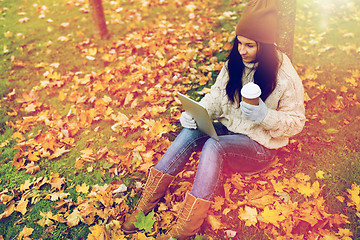 Image showing woman with tablet pc and coffee in autumn park