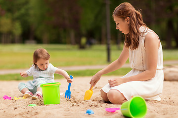 Image showing happy mother and baby girl playing in sandbox