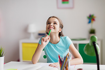 Image showing happy girl with book and notebook dreaming at home