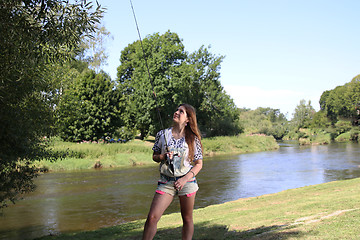 Image showing Young woman with summer sprouts and dungarees while fishing
