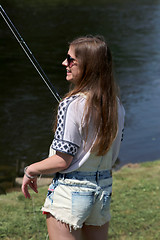 Image showing Young woman with summer sprouts and dungarees while fishing