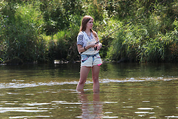 Image showing Young woman with summer sprouts and dungarees while fishing