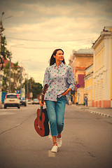 Image showing beautiful woman with a guitar walking down the street