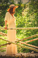 Image showing woman in a white dress and a summer hat on a bridge from a birch