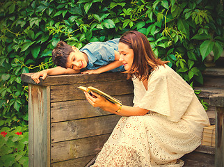 Image showing woman and a boy are reading a book on an ancient wooden porch