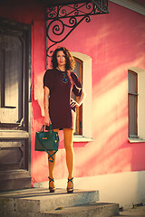 Image showing beautiful woman in a burgundy dress with a green hand bag