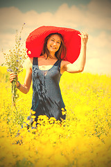 Image showing woman with a bouquet in a red hat on a sunny day amidst wildflow