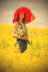 Image showing beautiful white woman in a red hat and with a bouquet of wildflo
