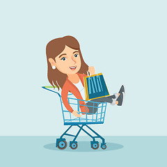 Image showing Young caucasian woman riding in shopping trolley.