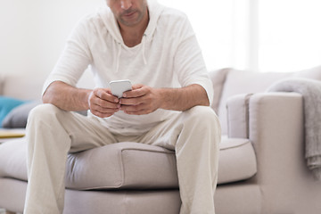 Image showing young man using a mobile phone  at home