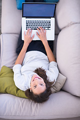 Image showing Young woman using laptop at home top view