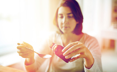 Image showing woman pouring medication from bottle to spoon