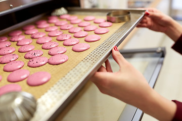 Image showing chef with macarons on oven tray at confectionery