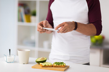 Image showing man photographing food by smartphone at home