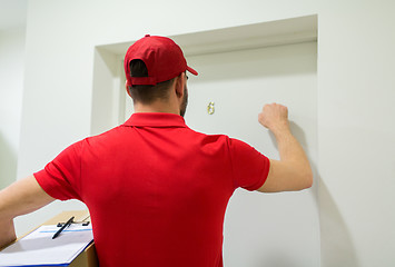 Image showing delivery man with parcel box knocking door