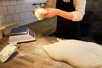 Image showing baker portioning dough with bench cutter at bakery