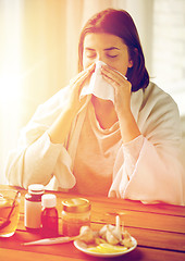 Image showing sick woman with medicine blowing nose to wipe