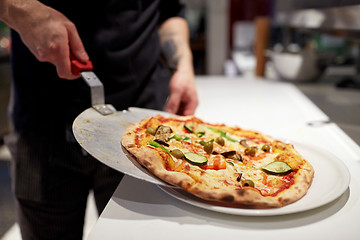 Image showing cook with baked pizza on peel at pizzeria