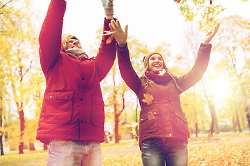 Image showing happy young couple throwing autumn leaves in park