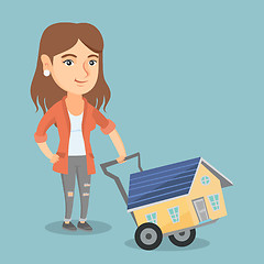 Image showing Young caucasian woman with a house on a trolley.