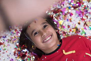 Image showing kid blowing confetti while lying on the floor