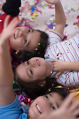 Image showing kids  blowing confetti while lying on the floor