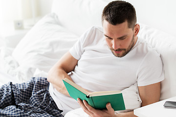 Image showing man reading book in bed at home