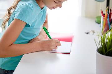 Image showing happy girl writing to notebook at home