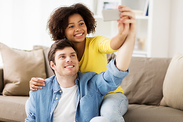 Image showing happy couple with smartphone taking selfie at home