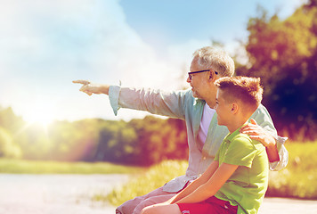 Image showing grandfather and grandson sitting on river berth