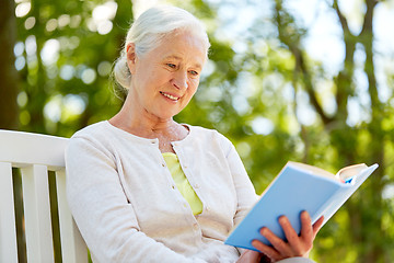 Image showing happy senior woman reading book at summer park