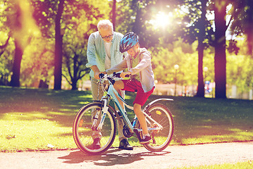 Image showing grandfather and boy with bicycle at summer park