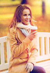 Image showing happy young woman drinking coffee in autumn park