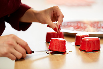 Image showing chef serving mirror glaze cakes at pastry shop