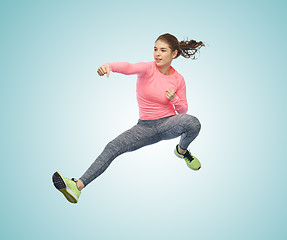 Image showing happy sporty young woman jumping in fighting pose