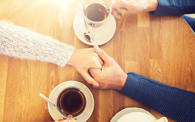 Image showing close up of couple holding hands at restaurant