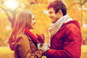 Image showing happy couple with maple leaves in autumn park