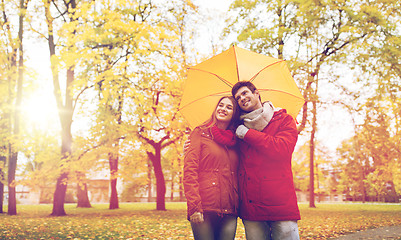 Image showing smiling couple with umbrella in autumn park