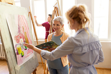 Image showing artists discussing painting on easel at art school